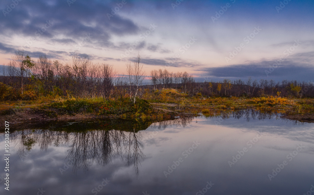 Beautiful autumn sunset on the lake. Reflection of trees in clean calm wat