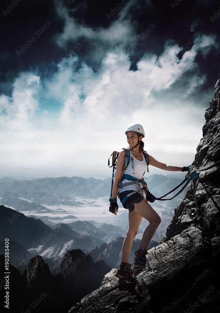 Frau klettert an einem Klettersteig (Via Ferrata) StockFoto Adobe Stock