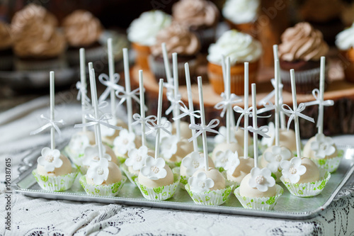 Candy bar on wooden wedding party with a lot of different candies, cupcakes, souffle and cakes. Decorated in brown and green colors, nature and eco theme, indoor
