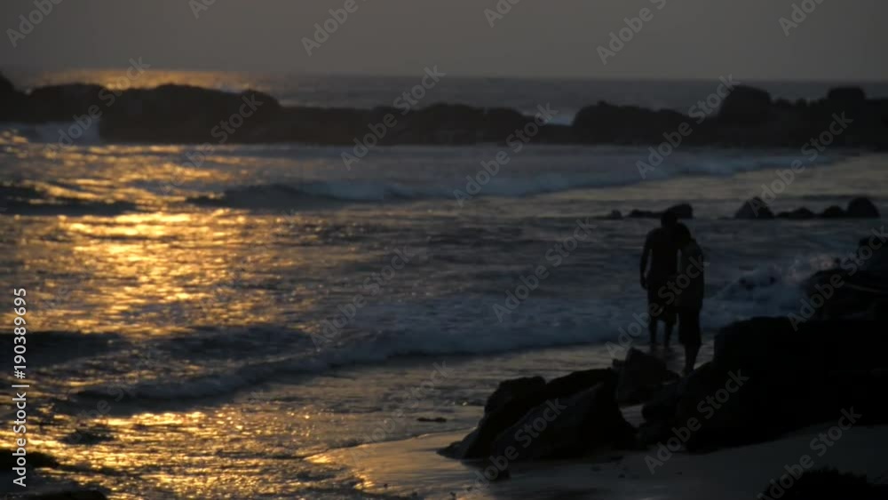 Silhouette of two people who walk along the seashore at sunset. Silhouette of two people who walk along the seashore at sunset.