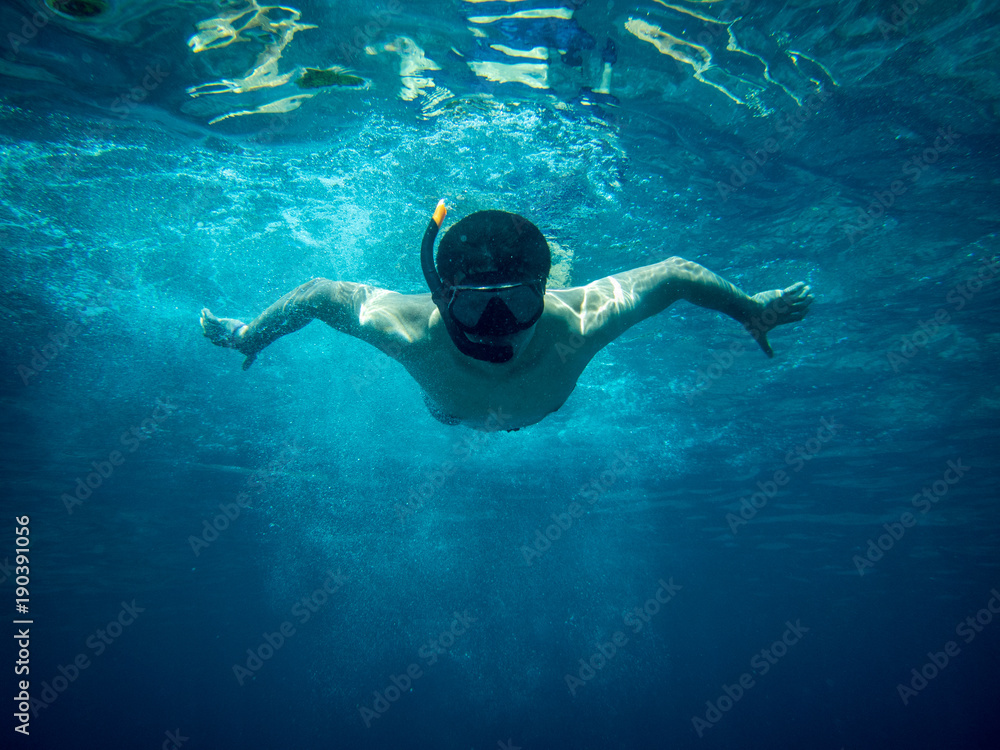 Young diver man swimming under blue sea
