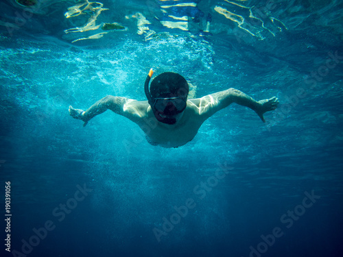 Young diver man swimming under blue sea