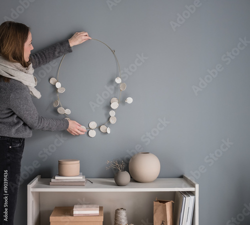 Interior Designer hängt eine Wanddekoration auf photo