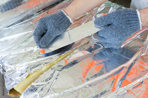 Man hand working insulation aluminum foil encapsulate.