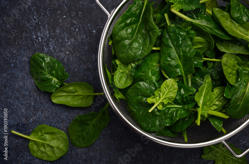 Fresh green spinach leaves on a dark concrete background  top view  flat lay.