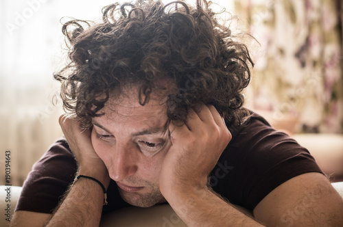 Single and bored young Caucasian man with curly hair at home photo