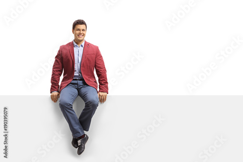 Elegant guy seated on a panel looking at the camera and smiling
