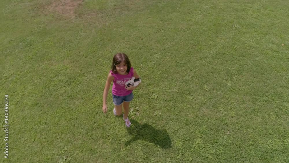 Young girl kid running in green field chasing drone camera Young girl kid running in green field chasing drone camera