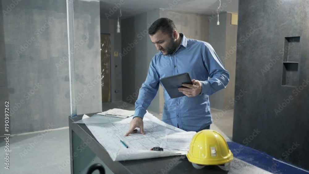 Young man working with tablet and blueprints by table at new home
Young man working with tablet and blueprints by table at new home