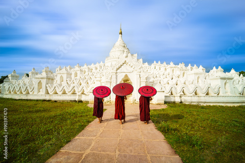 Three Asian young monk holding red umbrellas on the Mya Thein Tan Pagoda at Mingun, Mandalay Myanmar. photo