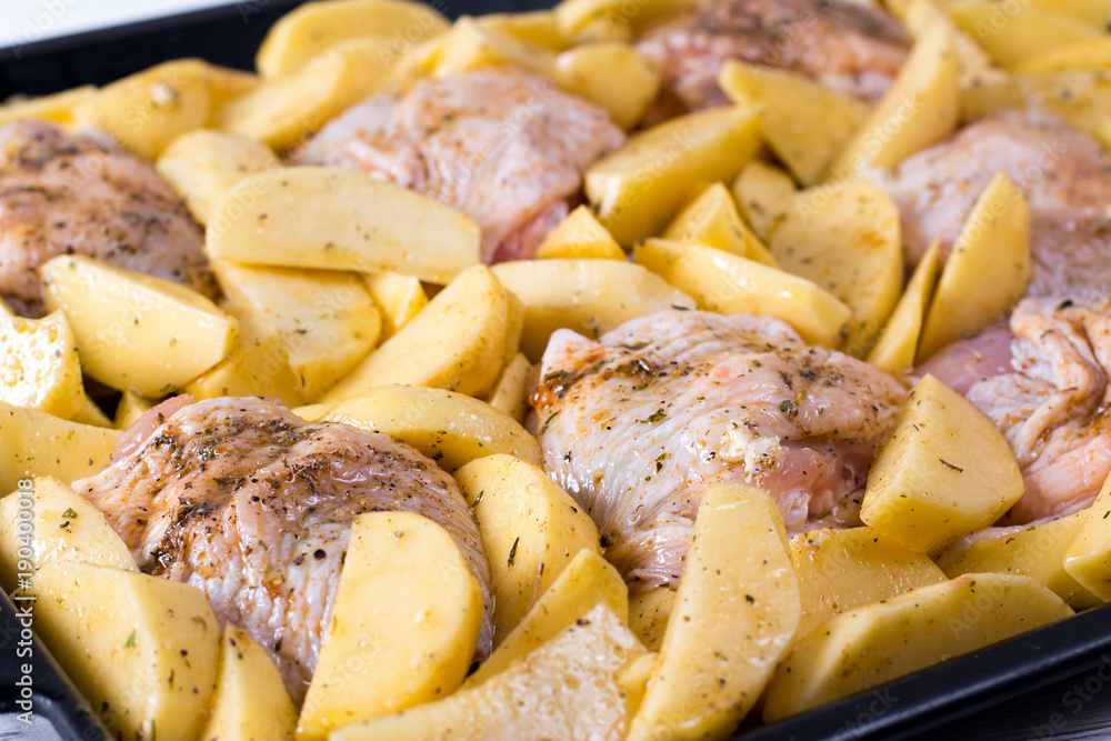 Raw chicken with raw potatoes in the form for baking, ready to be cooked