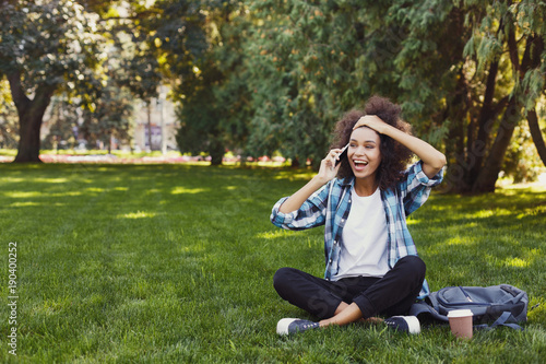 Young woman talking on phone and smiling outdoors © Prostock-studio