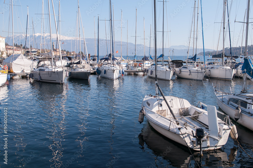 Il porto con le barche sul lago di Garda sullo sfondo della montagna innevata