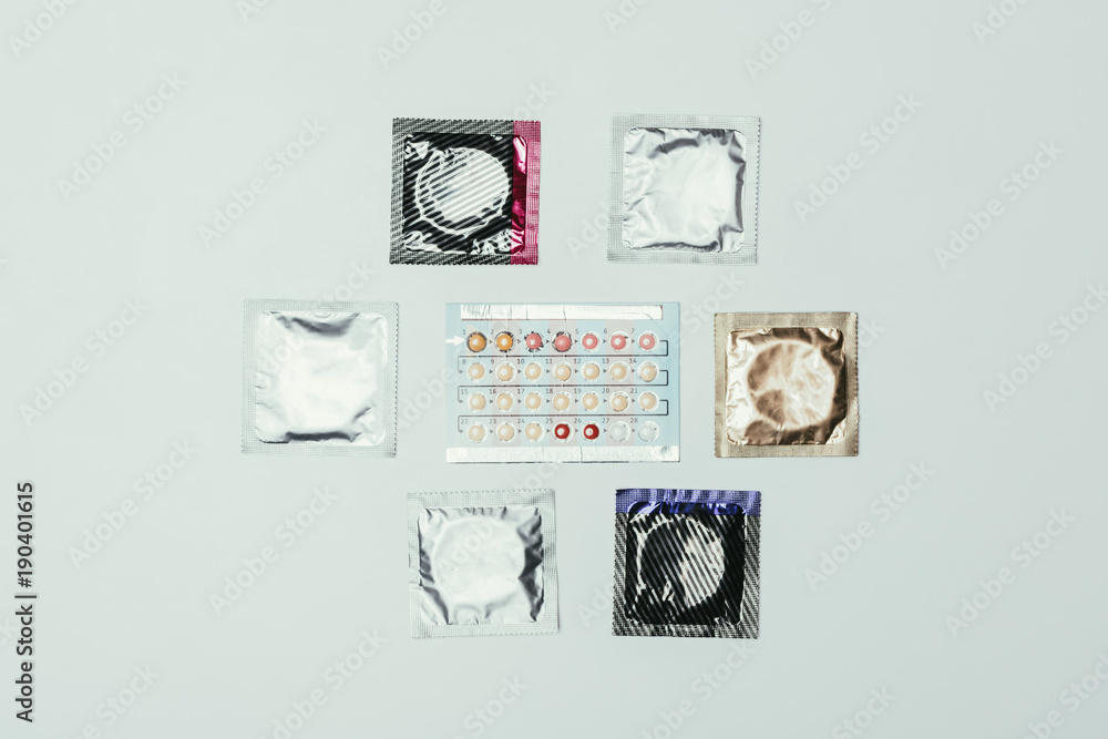 top view of arranged condoms and contraceptive pills isolated on grey top view of arranged condoms and contraceptive pills isolated on grey