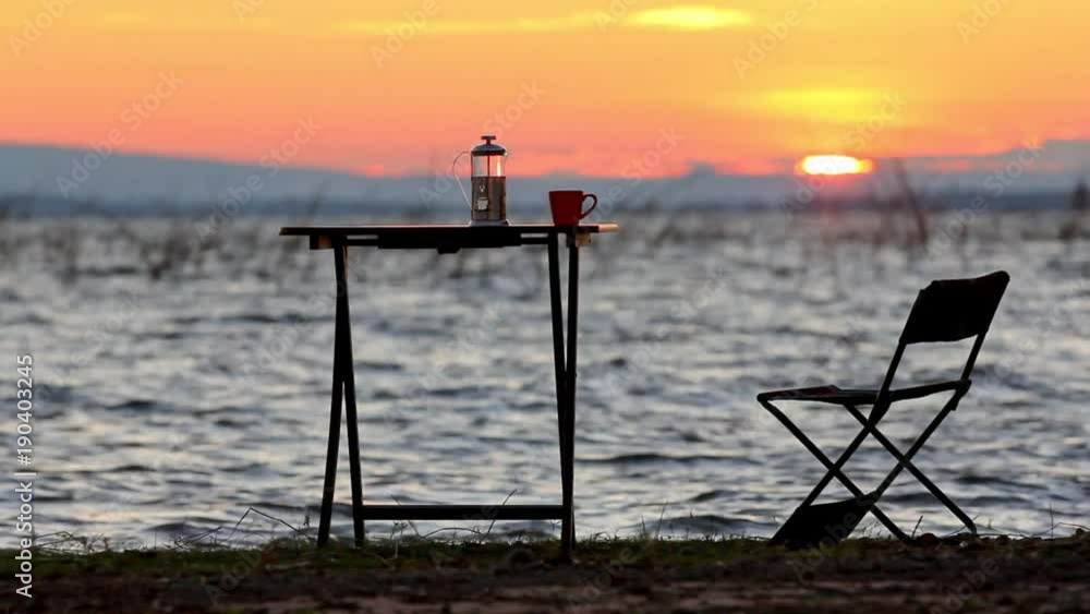 cup of coffee on the table beside the lake with sunrise background cup of coffee on the table beside the lake with sunrise background