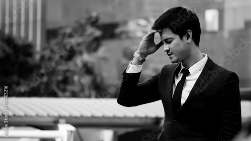 Bild auf Leinwand Frustrated Asian young business man standing in front of the office building