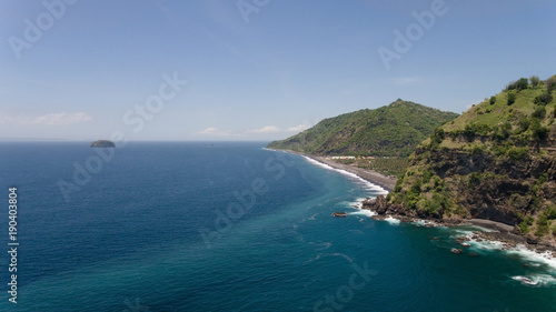 Rocky coast with high cliffs, sea coast, ocean, mountains, sea, beach, sky, clouds. Bali, sea surf with breaking waves on the coast, Indonesia. Ocean with waves and rocky cliff.