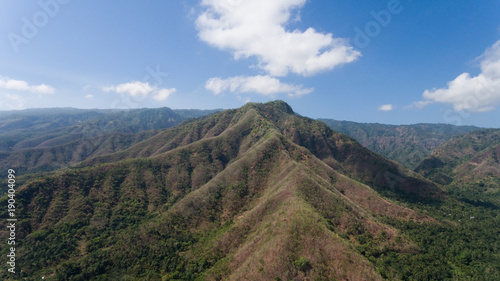 Aerial view of landscape, mountains covered with green forest, trees with sky and clouds, Bali,Indonesia. Slopes of the mountains are covered with forest in Asia. Travel concept.