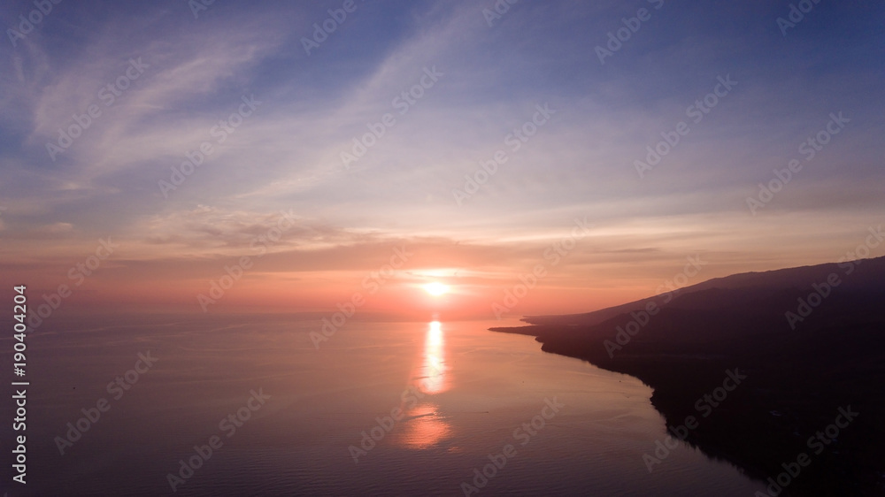 Sea coast at sunset. Aerial view of sunset on the ocean coast, sea, beach, sky, clouds. Bali, Indonesia. Sunset on the island of Bali.
