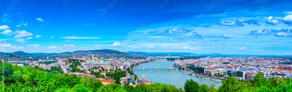 Panoramic cityscape view of hungarian capital city of Budapest from the Gellert Hill. The bridges connecting Buda and Pest across the river Danube. Summertime sunshine day, blue sky and green of trees