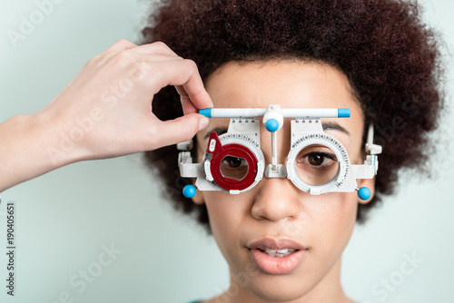 Woman having eyesight test with phoropter for new glasses at optician or eye doctor specialist photo