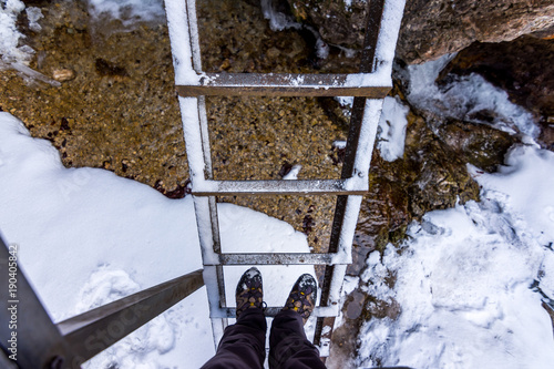 Outdoor ladder in national park Janosikove Diery. Tourist shoes on the ladder. Snow and winter photo