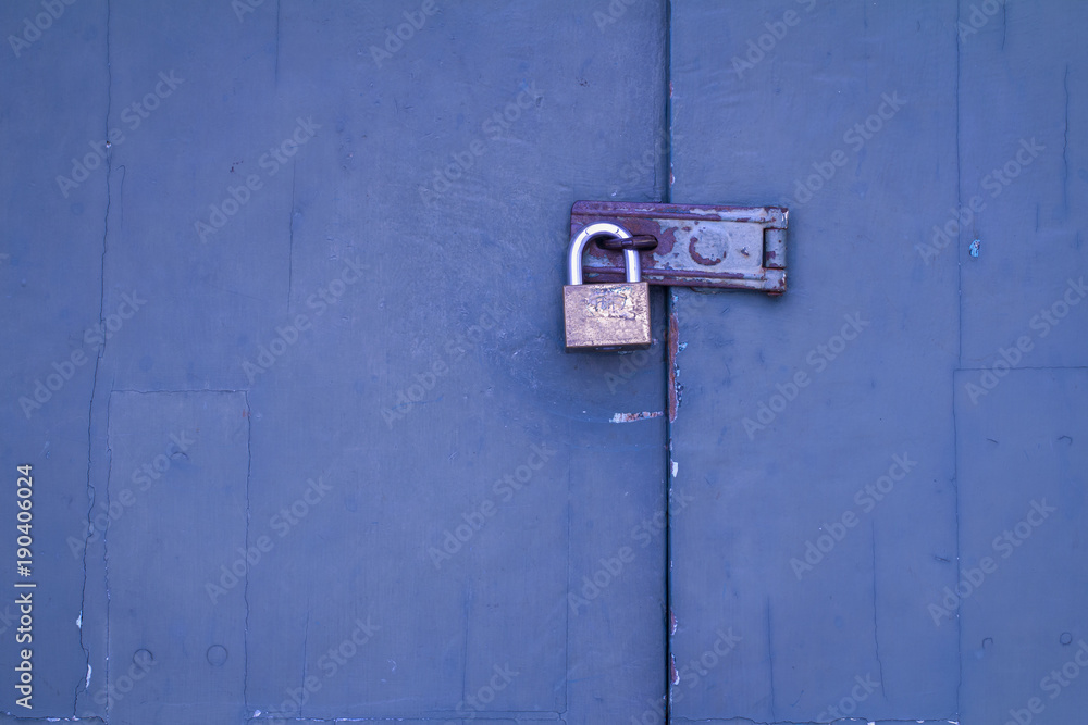 Old rusty padlock in locked status on blue wooden door with copy space for text input Old rusty padlock in locked status on blue wooden door with copy space for text input