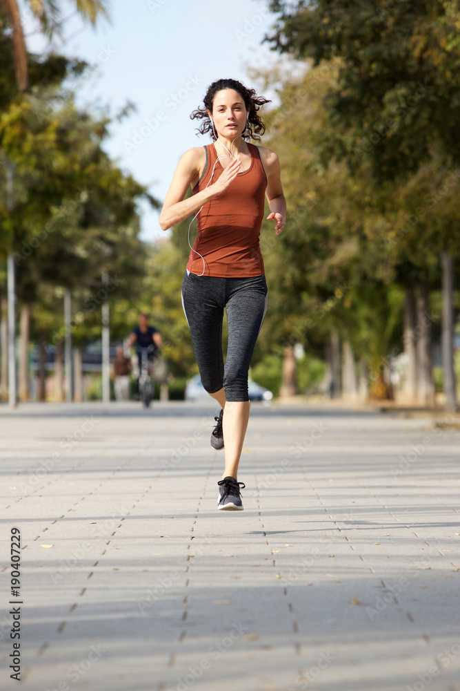 Full body healthy young sports woman jogging outdoors