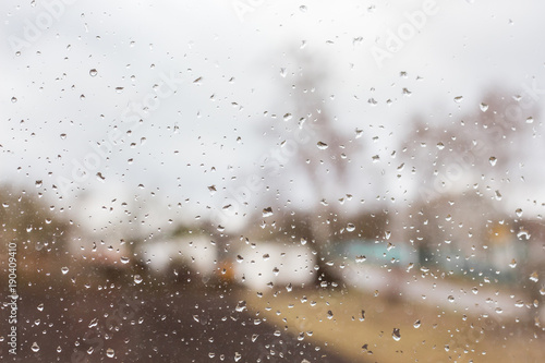 rain drops on clear glass, far away blurred houses and trees