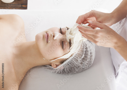 The beautician removes the face pack from the client's face photo