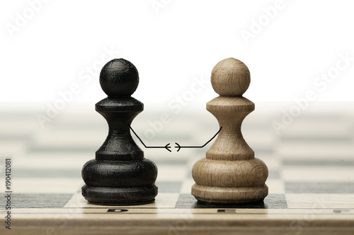 A pair of enemies reconciles and shakes hands at a meeting. Made from chess pawns