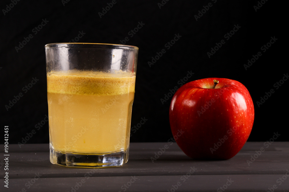 Red apple and a glass of freshly squeezed juice on a wooden background Red apple and a glass of freshly squeezed juice on a wooden background