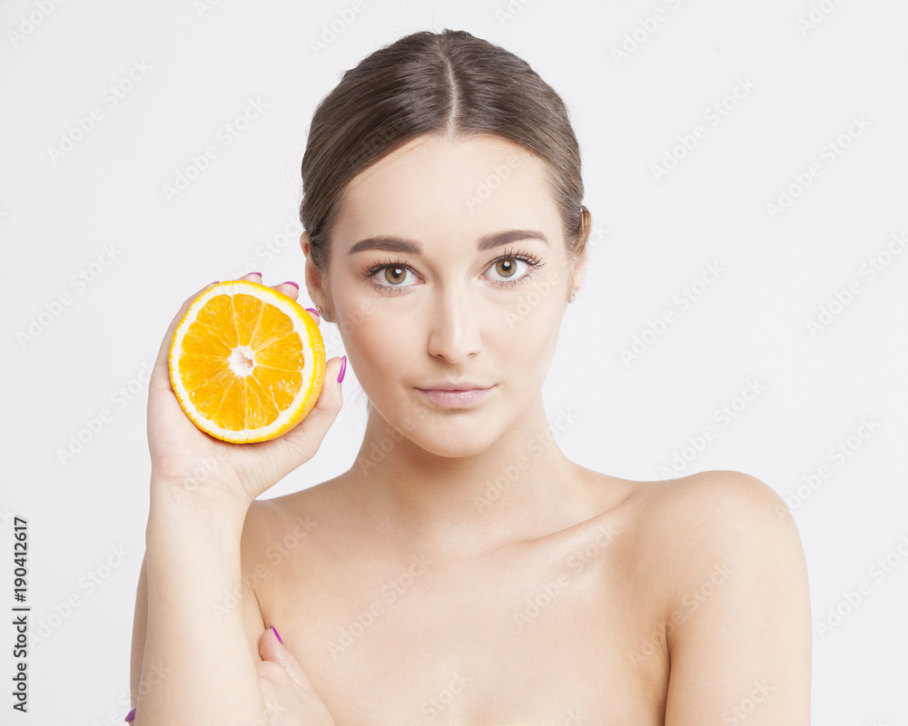 Portrait of a charming brunette holding an orange