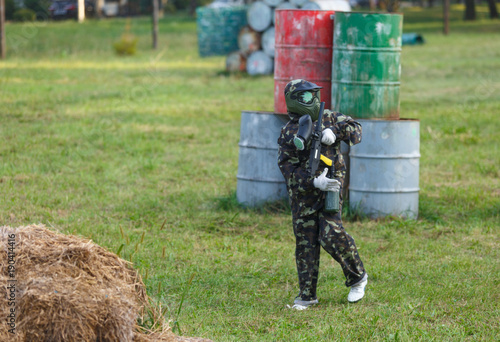 kids play paintball on special field with barrels, tires in the summer