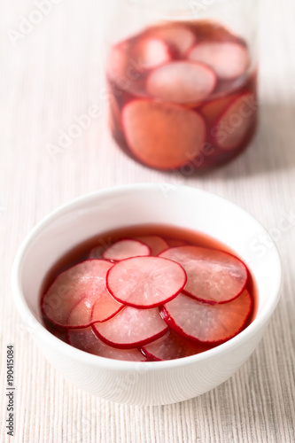 Fresh radishes cut in thin slices pickled in red wine vinegar with sugar and salt, photographed with natural light (Selective Focus, Focus on the front of the radish slice on the top)