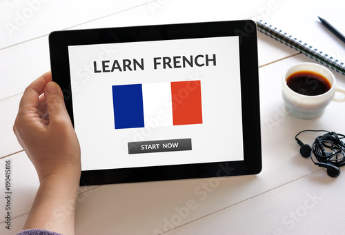 Hand holding digital tablet computer with learn French concept on screen. All screen content is designed by me