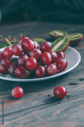Red grapes on a gray plate and wooden table 