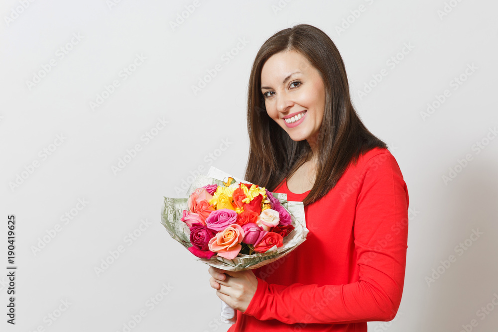 Young smiling woman in red clothes holding bouquet of beautiful roses flowers isolated on white background. Copy space for advertisement. St. Valentine's Day or International Women's Day concept. Young smiling woman in red clothes holding bouquet of beautiful roses flowers isolated on white background. Copy space for advertisement. St. Valentine's Day or International Women's Day concept.
