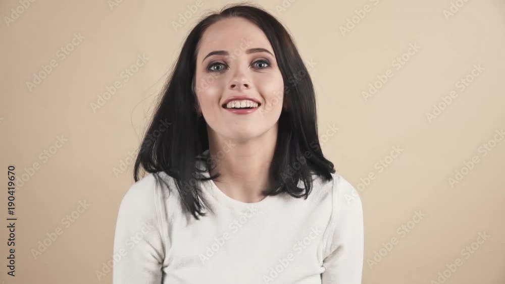 a young beautiful cute brunette on a beige orange background showing sarcasm, surprise emotions a young beautiful cute brunette on a beige orange background showing sarcasm, surprise emotions