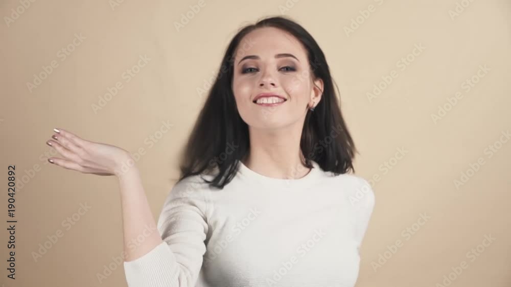 a young beautiful cute brunette on a beige orange background showing pride, joy, excellence, impeccability, happiness, cool emotions