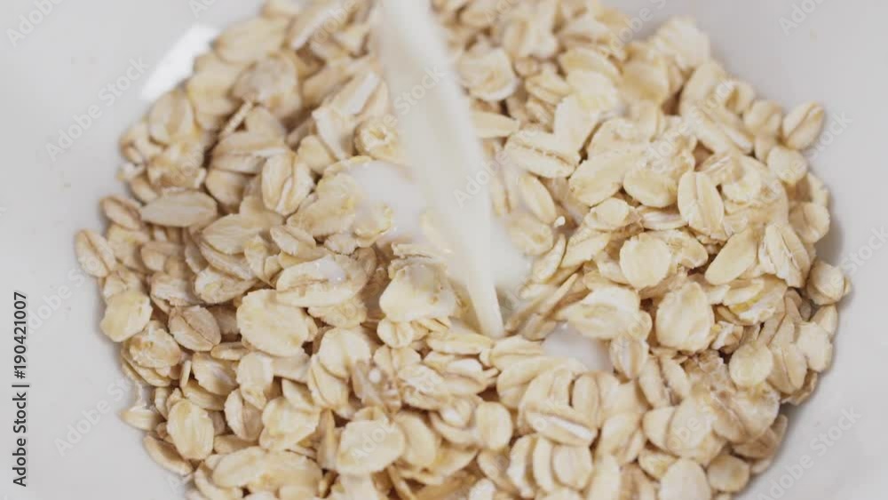 oat flakes pour milk white bowl closeup slow motion footage oat flakes pour milk white bowl closeup slow motion footage