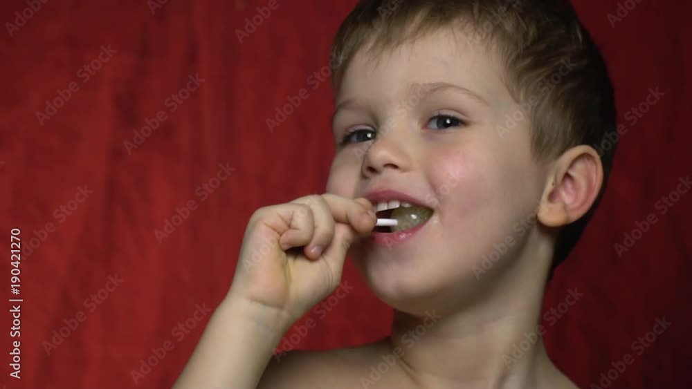 A boy sucks a candy and laughs A boy sucks a candy and laughs