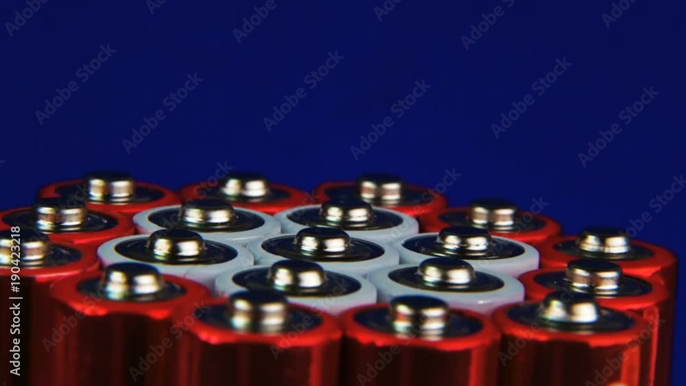 A pack of AA batteries, an extremely close-up, rotate. Batteries are red and white. On a blue background. A pack of AA batteries, an extremely close-up, rotate. Batteries are red and white. On a blue background.