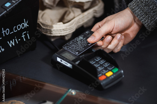 Customer is paying with contactless credit card in shop.