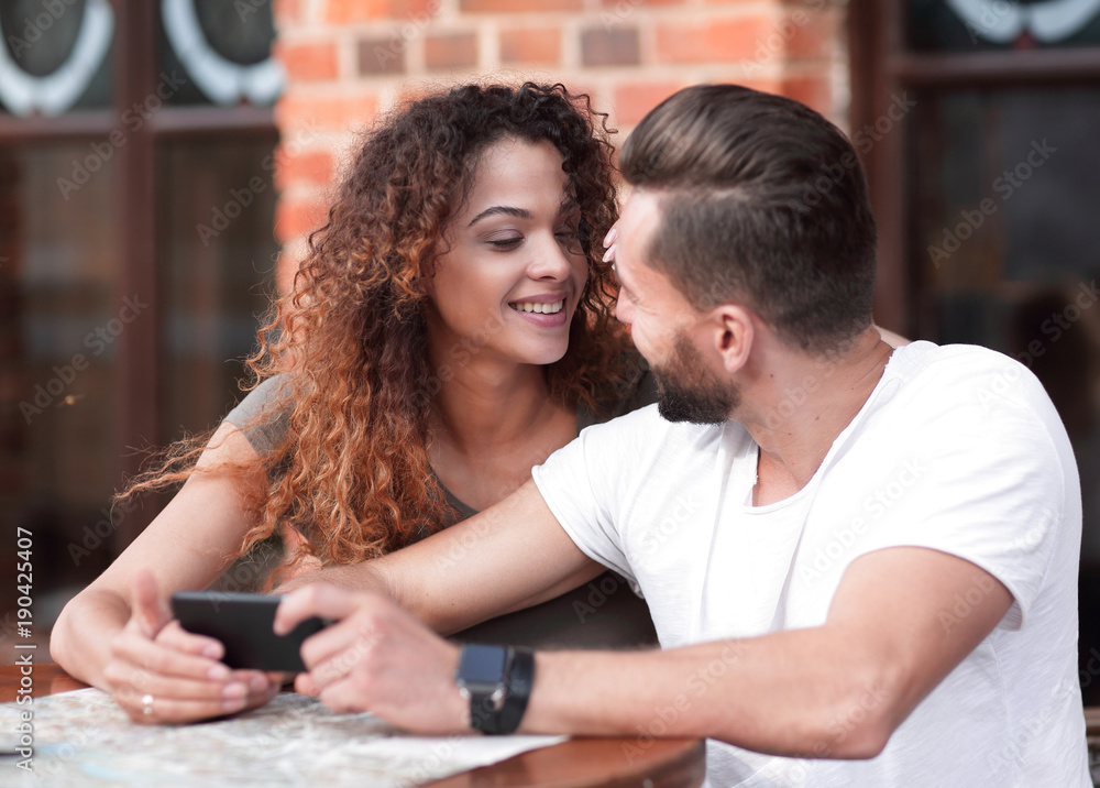 Happy loving  couple using a smartphone sitting in terrace