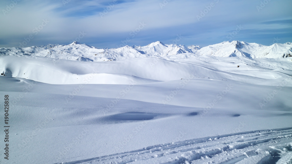 Fresh snow on ski pistes, covering valleys and peaks, with rugged mountain tops panorama, on a clear winter day, Les Trois Vallees, Alps, France .