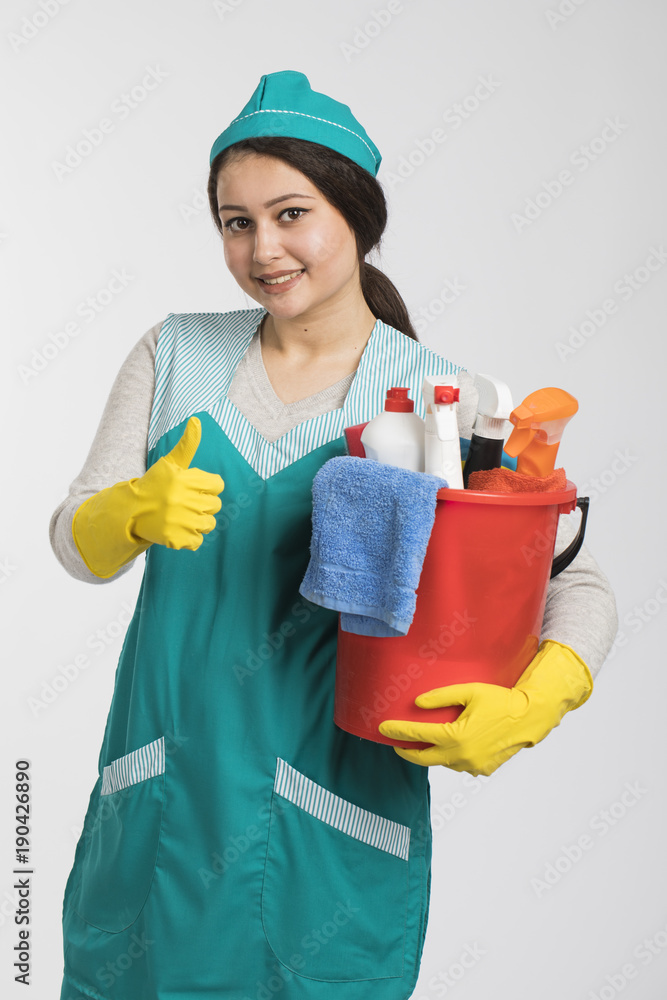 Young woman holding cleaning tools and products in bucket Young woman holding cleaning tools and products in bucket