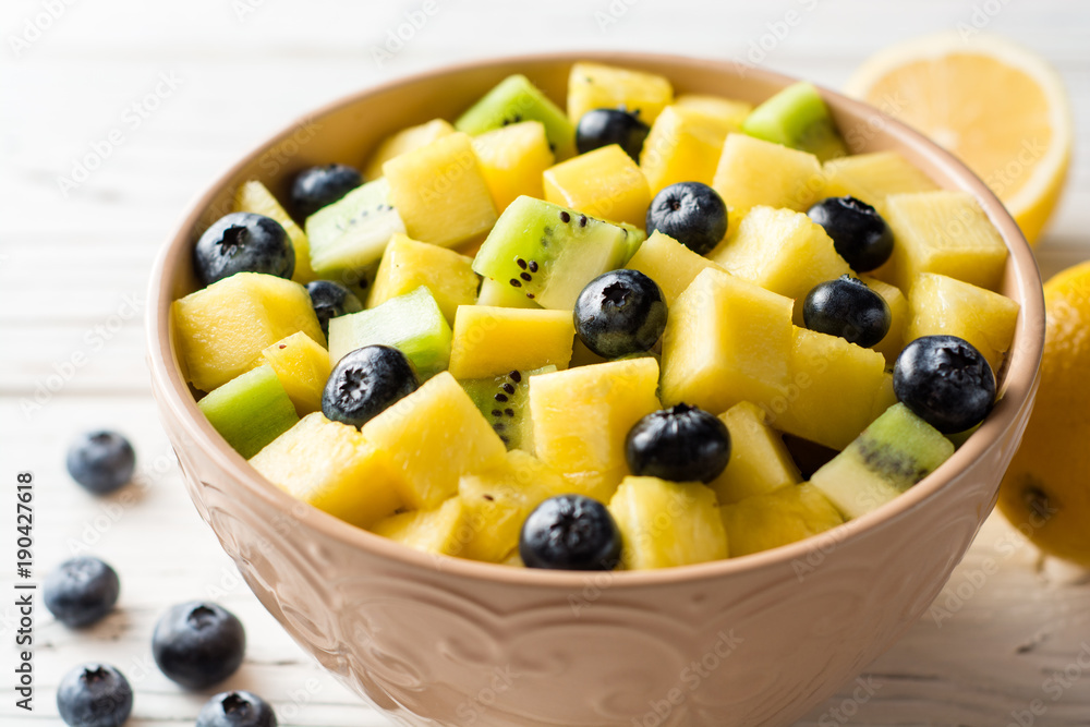 Fresh fruit salad with pineapple, mango, kiwi and blueberries on white wooden background. Fresh fruit salad with pineapple, mango, kiwi and blueberries on white wooden background.