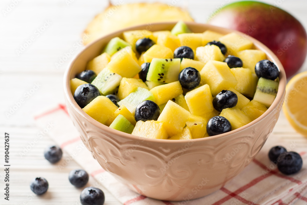 Fresh fruit salad with pineapple, mango, kiwi and blueberries on white wooden background. Fresh fruit salad with pineapple, mango, kiwi and blueberries on white wooden background.