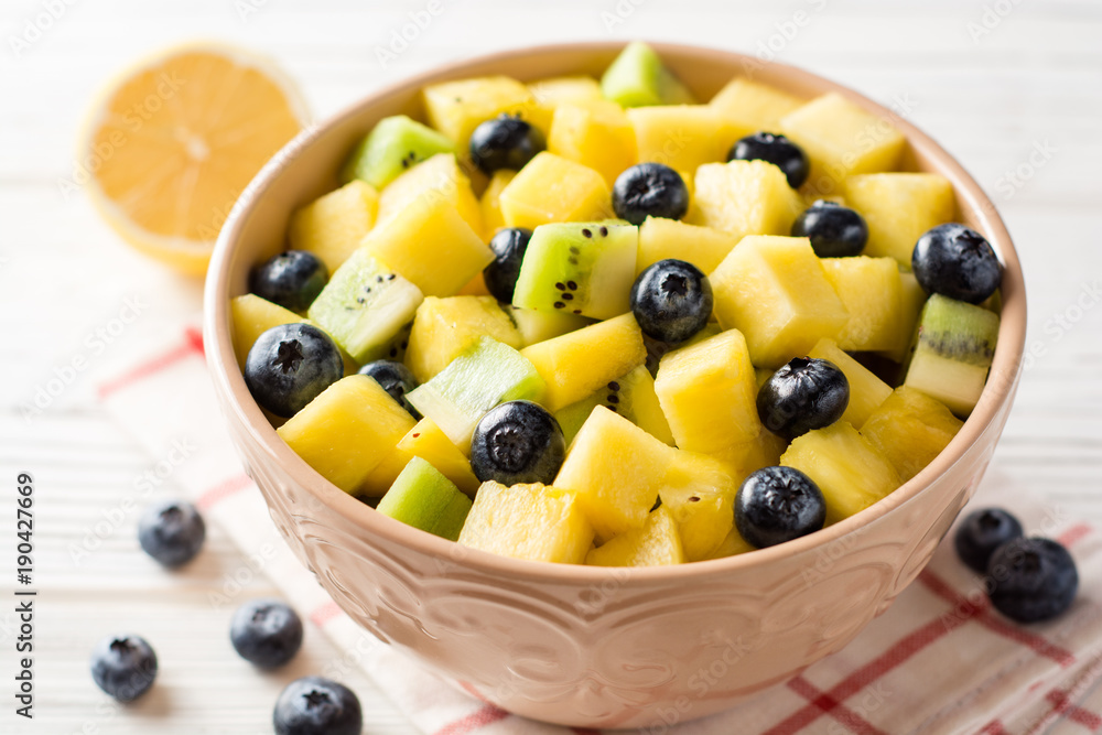 Fresh fruit salad with pineapple, mango, kiwi and blueberries on white wooden background. Fresh fruit salad with pineapple, mango, kiwi and blueberries on white wooden background.